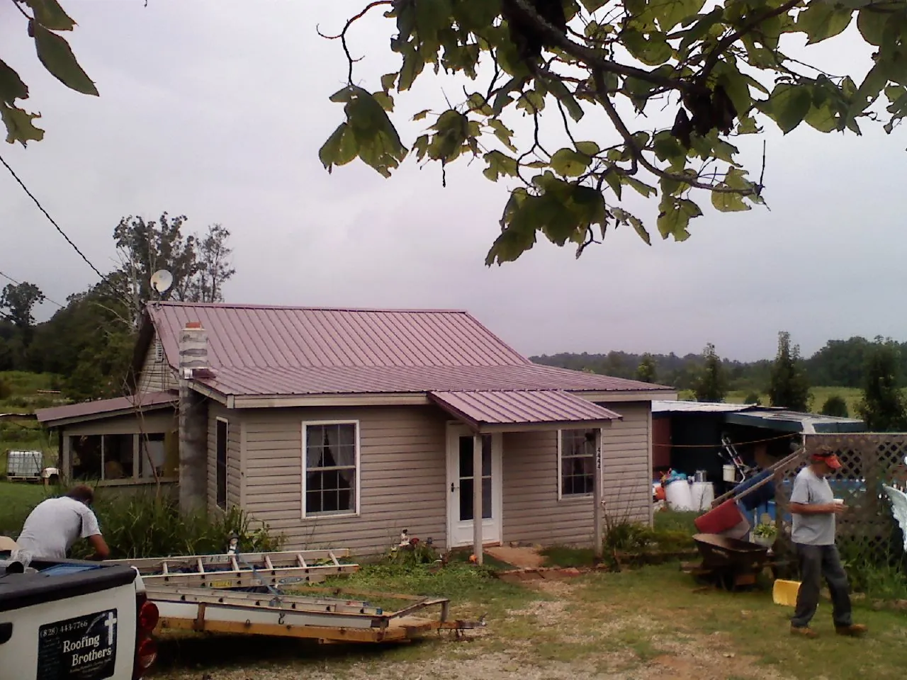 Crew finishing a mauve metal roof on a small farmhouse in Grandview